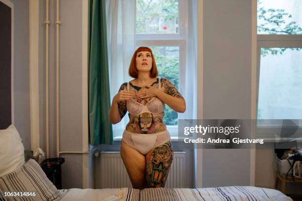 tattooed woman putting on lotion - body positive stockfoto's en -beelden