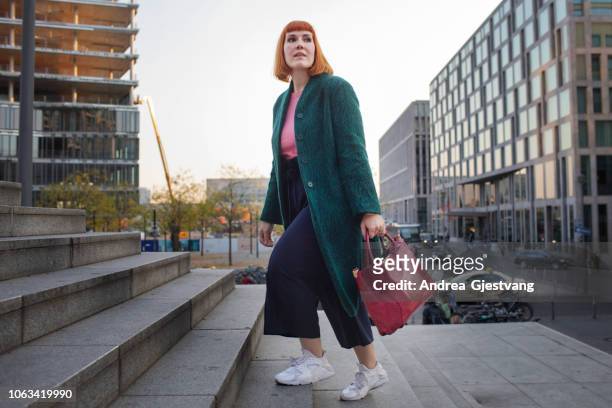 businesswoman walking through city - white purse stock-fotos und bilder