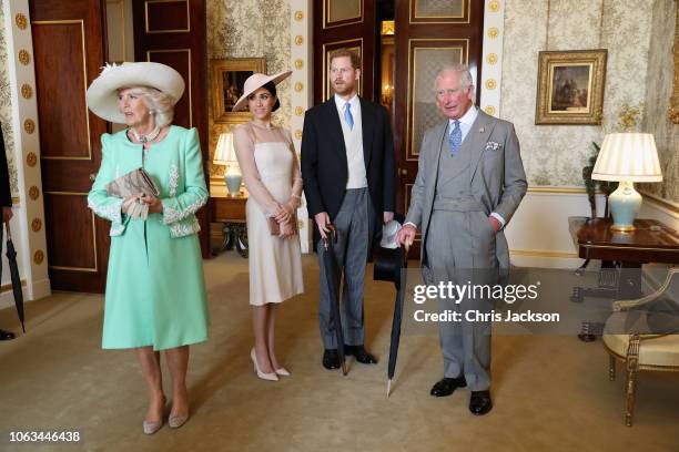 Prince Charles, Prince of Wales and Camilla, Duchess of Cornwall stand with Meghan, Duchess of Sussex and Prince Harry, Duke of Sussex as they look...