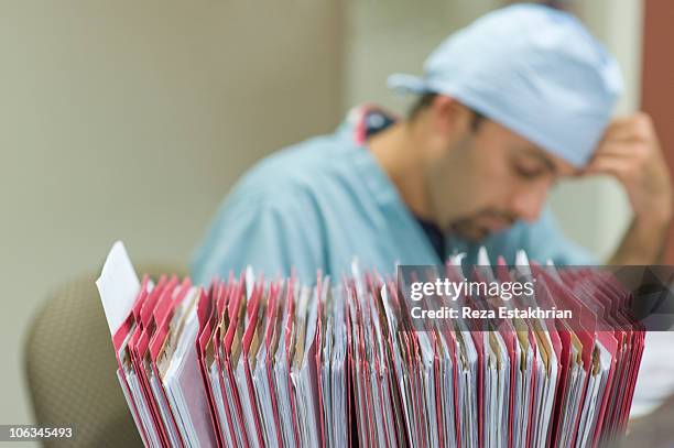 nurse with patient files in foreground - papierkram stock-fotos und bilder