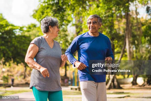 senior couple running at park - healthy older couple stock pictures, royalty-free photos & images