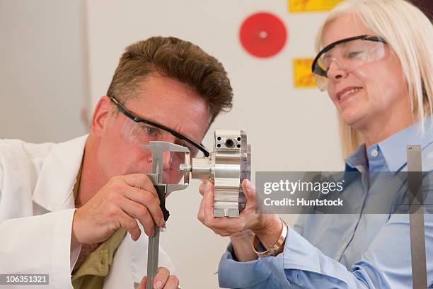 engineering professors measuring a machine part with a vernier calliper - vernier caliper stock-fotos und bilder