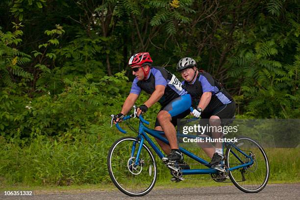 tandem disability racers with pilot in front and man with down syndrome - tandem bicycle stock pictures, royalty-free photos & images