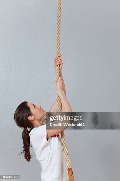 germany, berlin, young woman climbing rope in school gym - 爬山繩 個照片及圖片檔