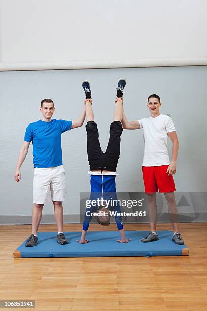 germany, berlin, young men holding woman leg, smiling - 3 gym stock-fotos und bilder