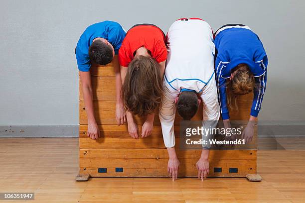 germany, berlin, young men and women leaning on vaulting horse - slab sided gymnastics vault stock pictures, royalty-free photos & images