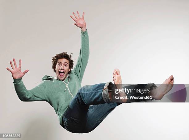 man falling against grey background, mouth open, portrait - chute photos et images de collection