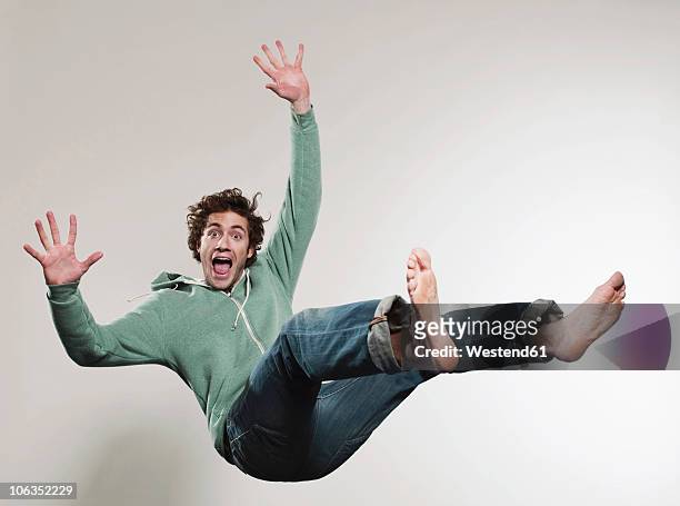 man falling against grey background, mouth open, portrait - cadere foto e immagini stock