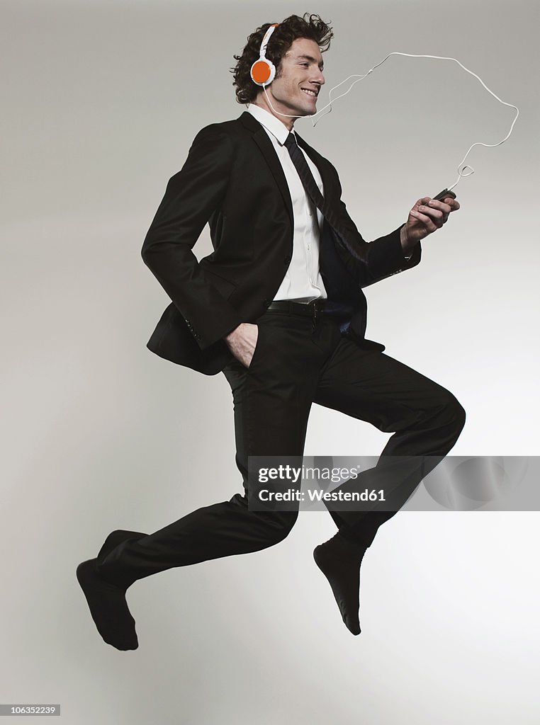 Businessman listening music and jumping, smiling