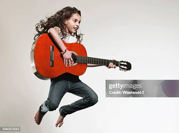 girl (12-13) playing guitar and jumping - guitar isolated stock-fotos und bilder