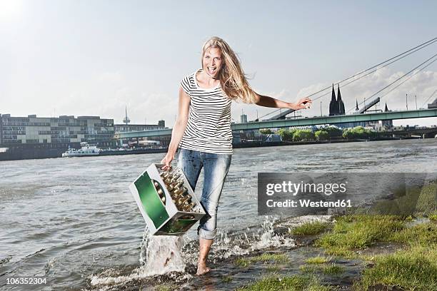 germany, cologne, woman carrying case of beer at rhein river - beer flowing stock pictures, royalty-free photos & images