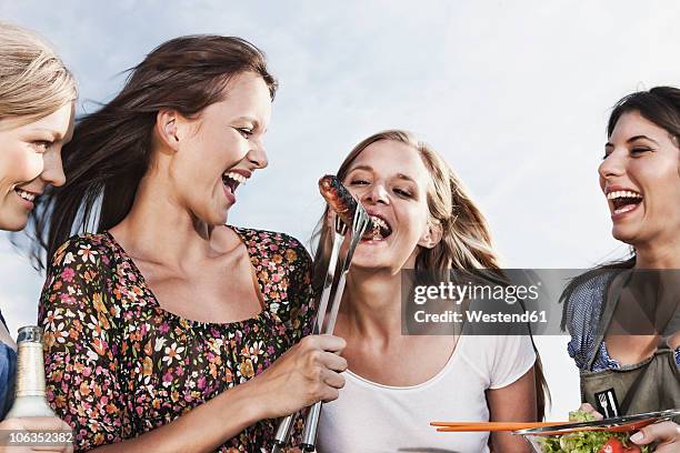 germany, cologne, women enjoying beer and sausages - beer bottle mouth stock-fotos und bilder