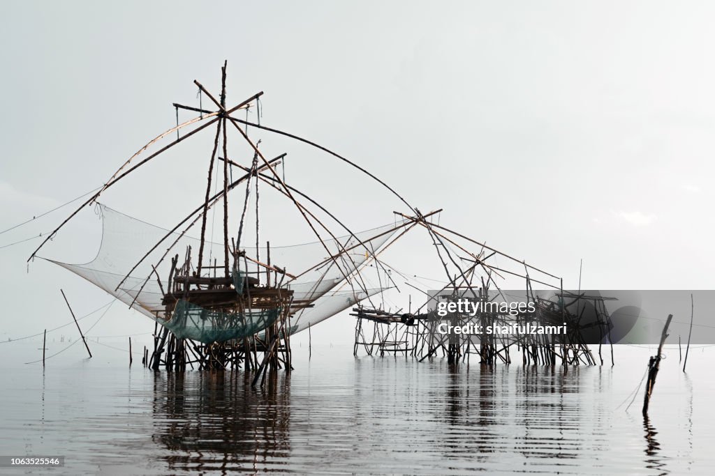 Traditional fishing nets made from bamboo and wood over cloudy sunrise at lake Thale Noi, Phatthalung, Thailand.