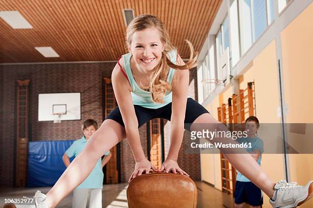 germany, emmering, girl jumping with boys standing in background - gymnastics vault stock pictures, royalty-free photos & images