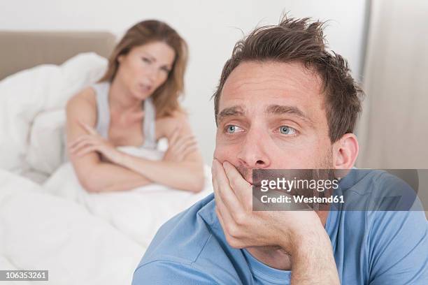 germany, man thinking with woman sitting in background - frustration man stock pictures, royalty-free photos & images
