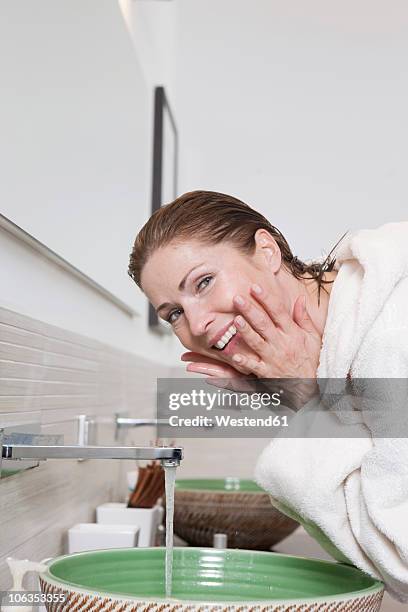 germany, woman washing face, smiling, portrait - gesichtsreinigung stock-fotos und bilder