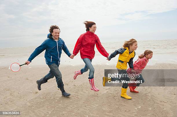 germany, st. peter-ording, north sea, family holding hands and running on beach - boy and girl running along beach holding hands stock-fotos und bilder