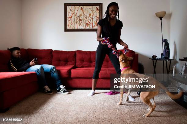Professional wrestler Gia Scott plays with her boyfriend and professional wrestler Deion Epps' dog as he plays on his smartphone at their home in...