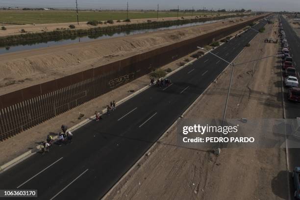 Central American migrants -mostly Hondurans- moving in a caravan towards the United States in hopes of a better life, walk along the metal fence on...