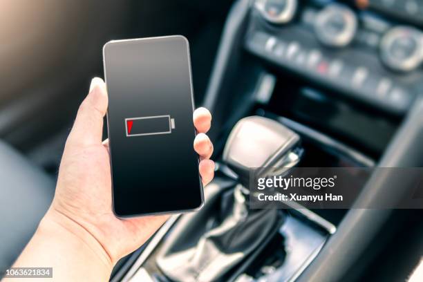 holding smartphone in car - battery low stock-fotos und bilder
