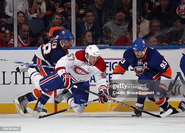 Benoit Pouliot of the Montreal Canadiens is tripped up by Jack Hillen and Doug Weight of the New York Islanders at the Nassau Coliseum on October 29,...