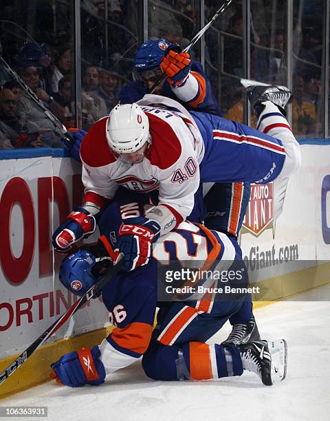 Maxim Lapierre of the Montreal Canadiens is pushed over Matt Moulson of the New York Islanders at the Nassau Coliseum on October 29, 2010 in...