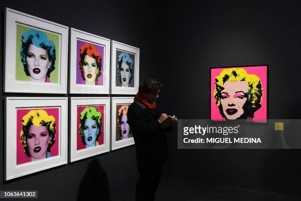 Visitor stands by British street artist Banksy's 2005 silkscreens "Kate Moss" and US artist Andy Warhol's 1968 silkscreen "Marilyn Monroe" during a...