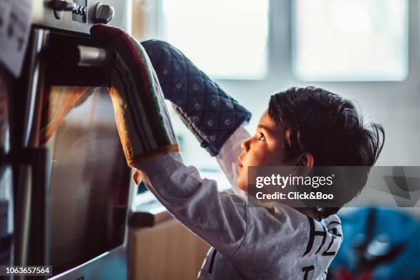 cute little boy in the kitchen cooking - backofen stock-fotos und bilder