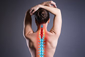 Pain in the spine, woman with backache on gray background, back injury