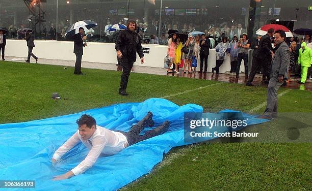 Race-goers slide along the ground in the rain during the AAMI Victoria Derby Day at Flemington Racecourse on October 30, 2010 in Melbourne, Australia.