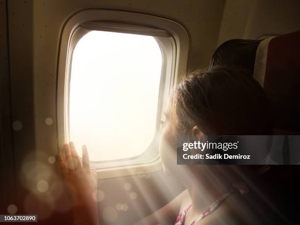 little girl looking through airplane window with beam of light - sun rays through window bildbanksfoton och bilder