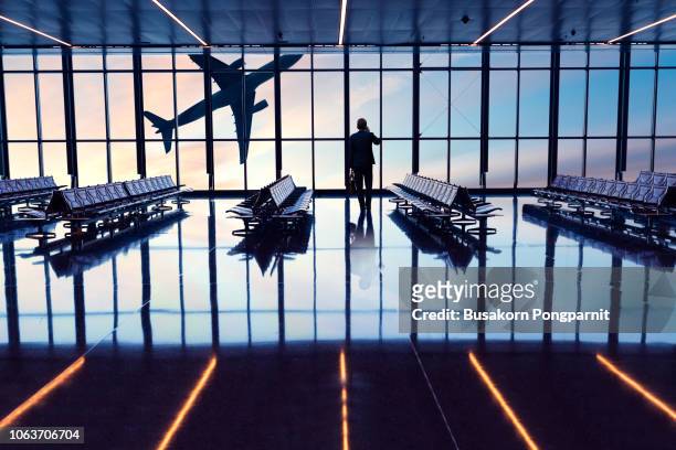 businessman at airport looking at airplane taking off - doha airport stock pictures, royalty-free photos & images