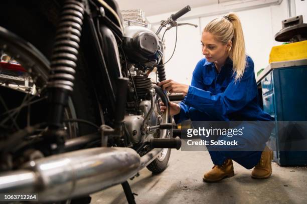 woman repairing motorcycle - motorcycle mechanic stock pictures, royalty-free photos & images
