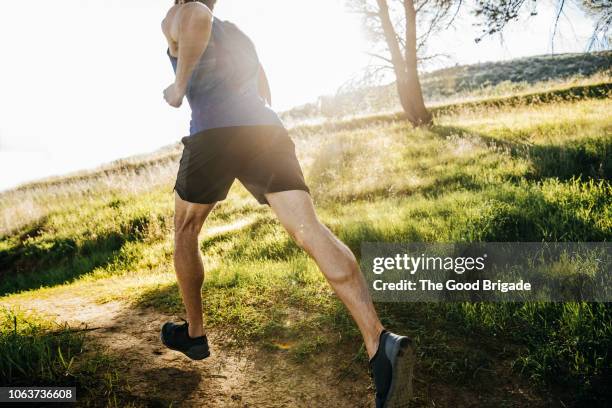 mid adult man jogging in park on sunny day - runner man stockfoto's en -beelden