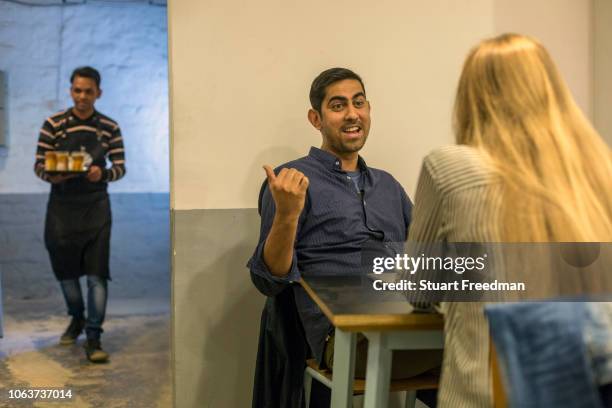 Couple chat at Blue Tokai coffee shop in Champa Gali, New Delhi, India. Champa Gali is the latest and most intimate of Delhi's urban creative...