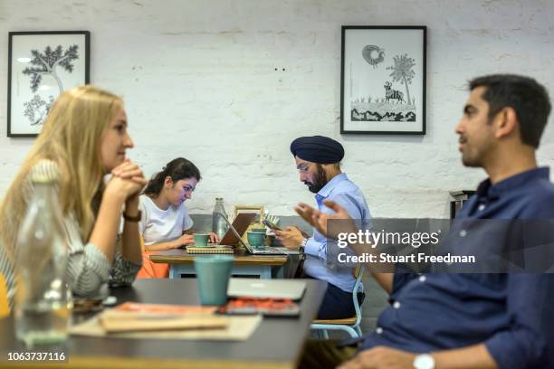 Couple chat at Blue Tokai coffee shop in Champa Gali, New Delhi, India. Champa Gali is the latest and most intimate of Delhi's urban creative...