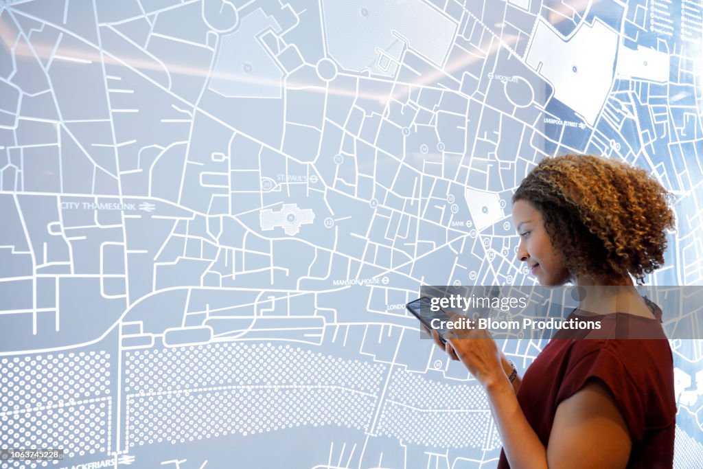 Woman using a smartphone, next to a futuristic digitally generated display