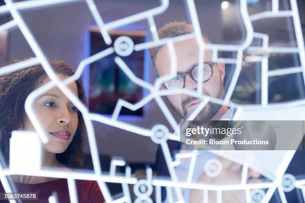 business people looking at a futurisitic digitally generated display - prédire lavenir photos et images de collection