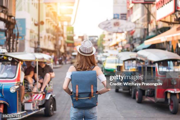 the back of a young woman walking and walking along the pedestrian street in the evening in bangkok, thailand, travelers and tourists. - backpacker woman stock-fotos und bilder