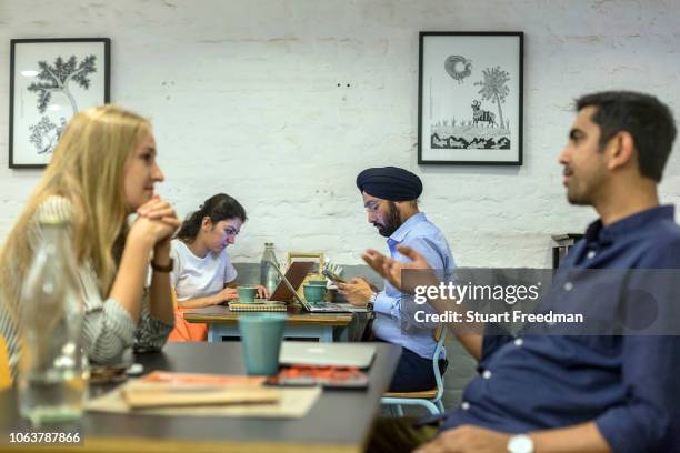 Couple chat at Blue Tokai coffee shop in Champa Gali, New Delhi, India. Champa Gali is the latest and most intimate of Delhi's urban creative...