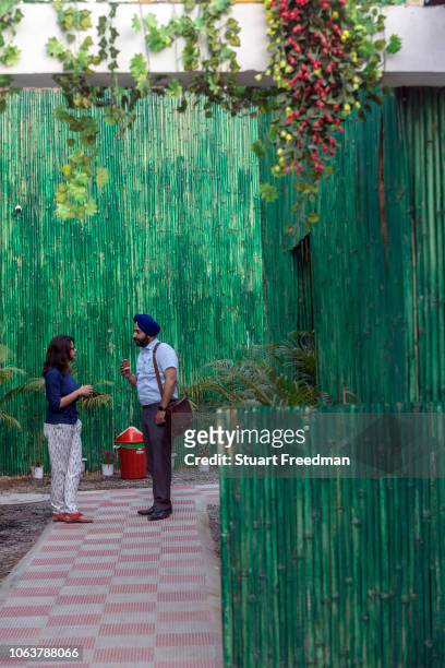 Couple chat and share coffee in the garden of a production house in Champa Gali, New Delhi, India. Champa Gali is the latest and most intimate of...