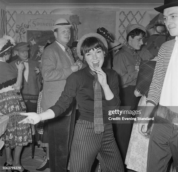 English fashion designer Mary Quant eating a lollipop at a party, 27th January 1959. With her is her husband, Alexander Plunket Greene .