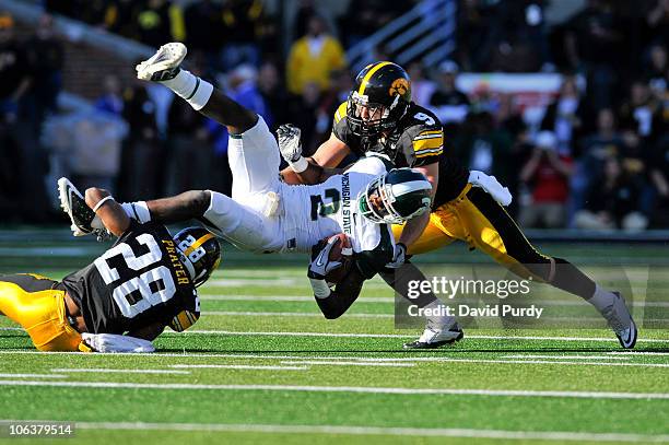 Wide receiver Mark Bell of the Michigan State Spartans is tackled by defensive back Tyler Sash of the University of Iowa Hawkeyes and his teammate...