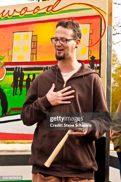 View of American religious activist and author Shane Claiborne as he holds a hand rake during a demonstration at an anti-gun rally in the Englewood...