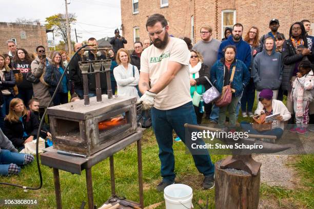 As a crowd watches, American religious activist and blacksmith Michael Martin of the RAWTools organization uses a portable forge to make garden tools...