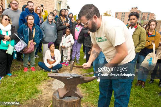 As a crowd watches, American religious activist and blacksmith Michael Martin of the RAWTools organization uses a hammer and anvil to form a garden...