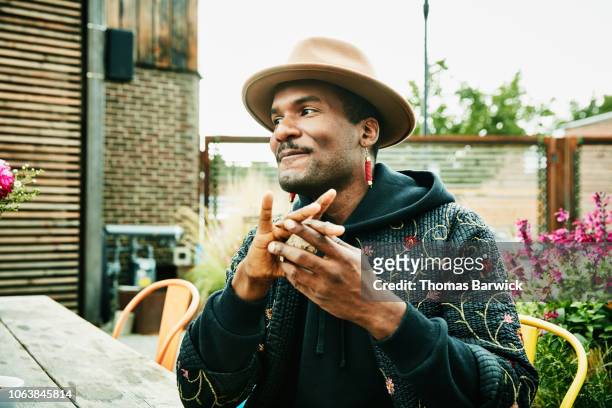smiling man hanging out with friends at outdoor bar - green coat stock pictures, royalty-free photos & images