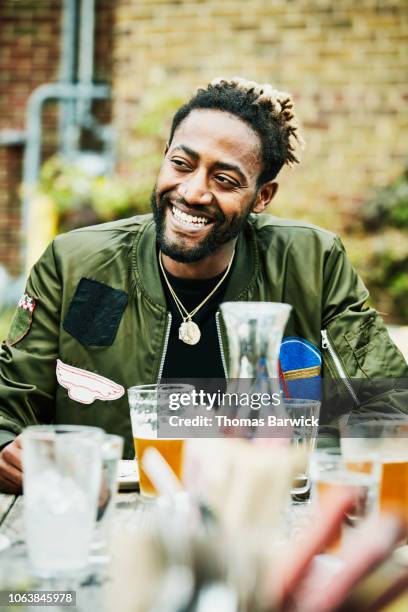 smiling man seated with friends at table at outdoor restaurant - bar atmosphere stock pictures, royalty-free photos & images