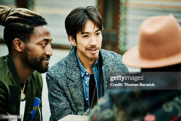 smiling friends in discussion while hanging out at outdoor restaurant - handsome native american men stock pictures, royalty-free photos & images