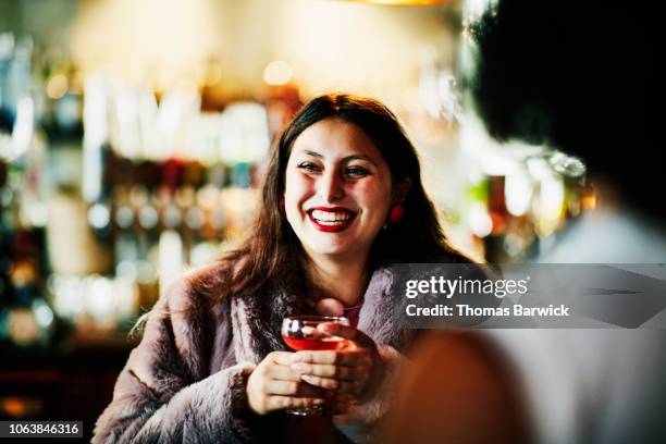 Laughing woman sharing drinks with friends in bar